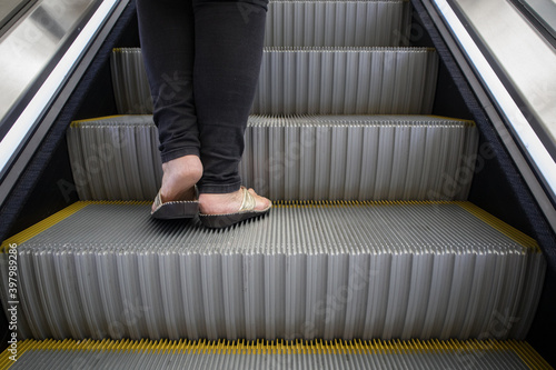 Bottom the legs and feet of person standing on an escalator