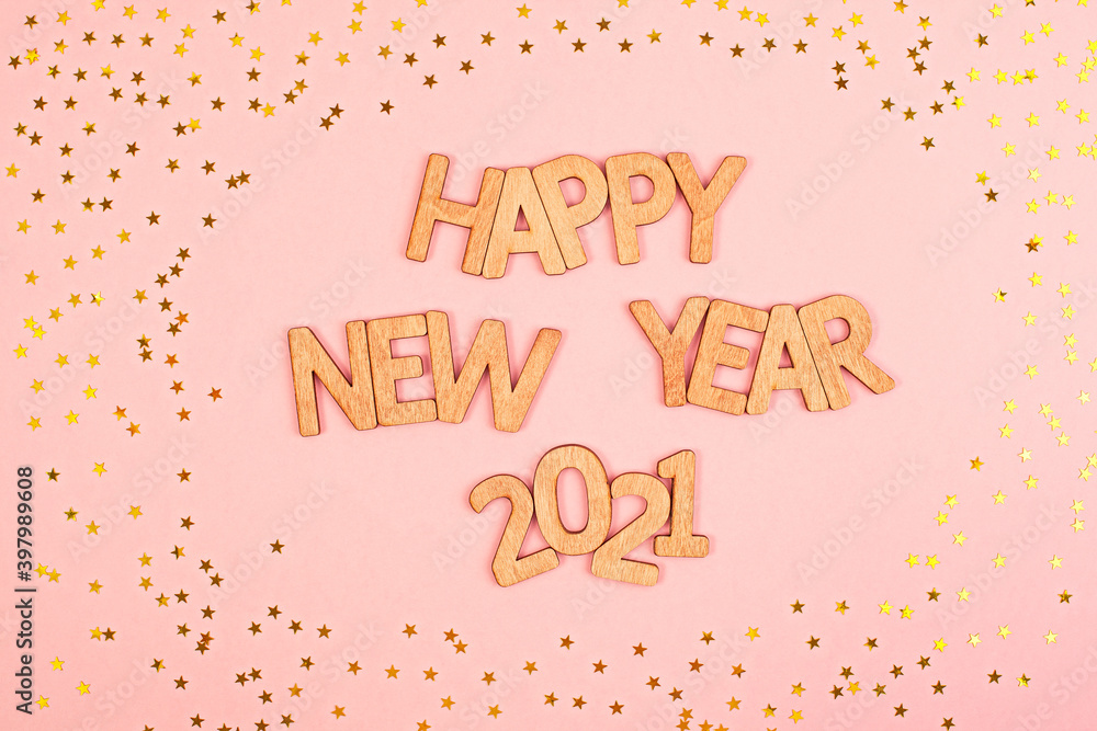 Cheerful wooden lettering happy new year 2021 on a soft pink background with gold stars.