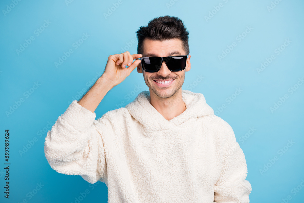 Photo portrait of confident man with stubble touching glasses isolated on pastel blue colored background Photo portrait of confident man with stubble touching glasses isolated on pastel blue colored background