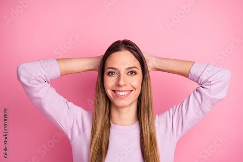 Close-up portrait of pretty cheerful straight-haired girl holding hands behind head free time isolated over pink pastel color background