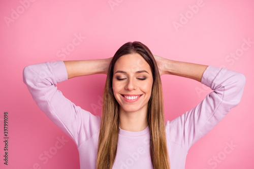 Close-up portrait of lovely dreamy straight-haired girl holding hands behind head relaxation isolated over pink color background