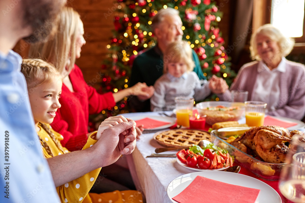 family having christmas dinner and praying before meal, multi-generation family enjoy celebrating new year with loved ones