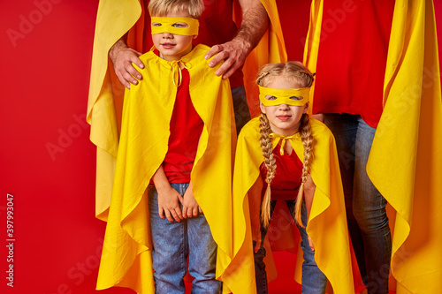 funny children in supehero mask and cloaks isolated on red background, little kids looking forward