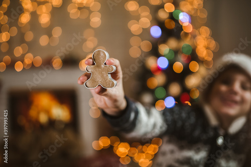 A boy in a Santa Claus hat is holding a ginger cookie model