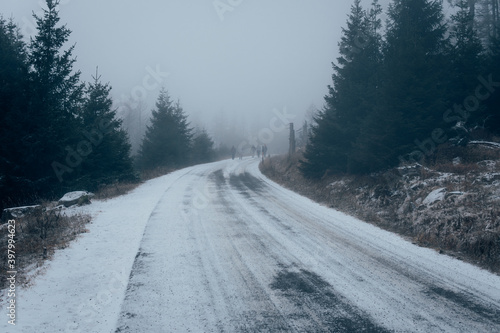 Verschneite Brockenstraße mit Nebel und Wanderer