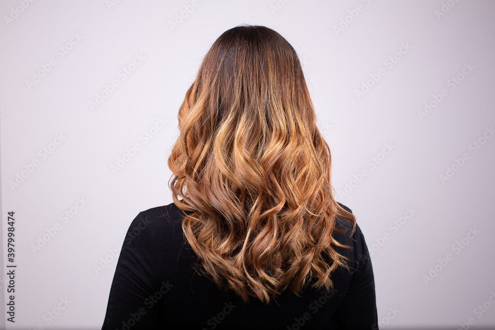 Obraz premium Back view portrait of beautiful curly dark blonde woman wearing black sweater