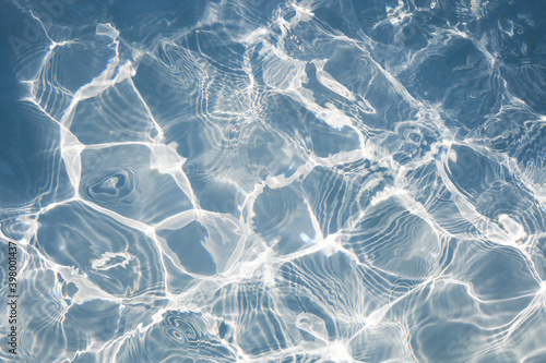 Blue water swimming surface with bright sun light reflections. for background photo