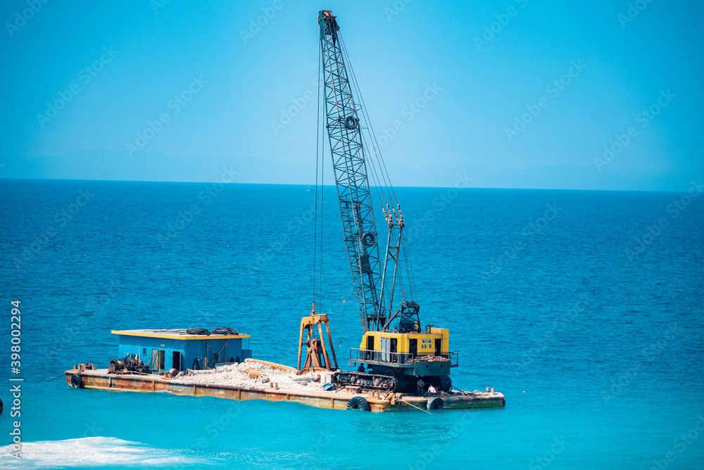 Fototapeta premium The ship is mining stone and sand in the sea