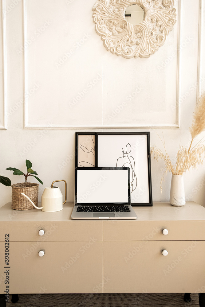 Obraz premium Laptop computer with blank screen on table with boho decorations. Minimal boho styled interior design template with mockup copy space.