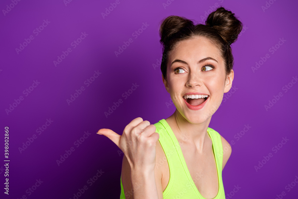 Photo of surprised girl point thumb finger copyspace wear green singlet isolated over purple color background Photo of surprised girl point thumb finger copyspace wear green singlet isolated over purple color background