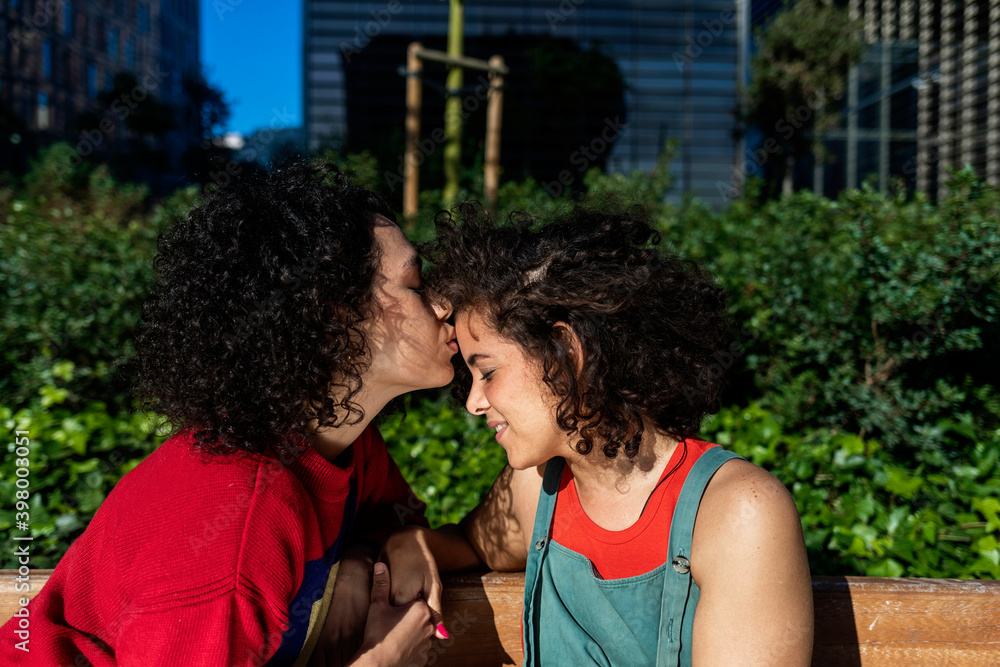 Fototapeta premium Smiling lesbian couple embracing and relaxing on a park bench