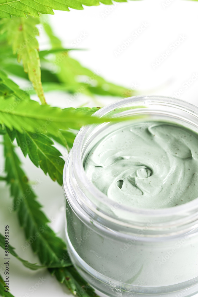 Green cannabis plant and jar with a moisturizing cream Green cannabis plant and jar with a moisturizing cream
