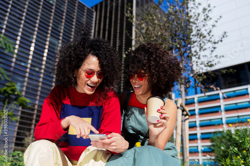 Beautiful women using a mobile in the street while sitting on a bench outdoors