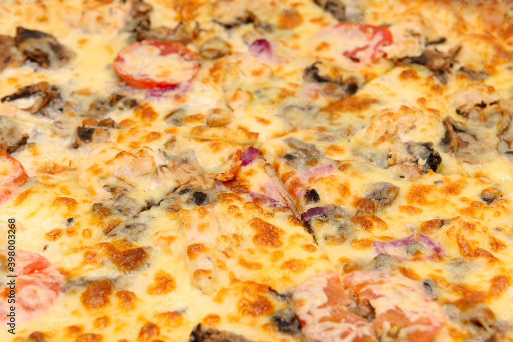 Surface of a delicious pizza with cheese, tomatoes and other ingredients