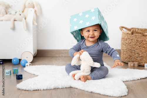 Happy baby in playroom with basket on head