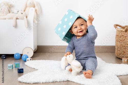 Smiling baby in playroom with basket on head