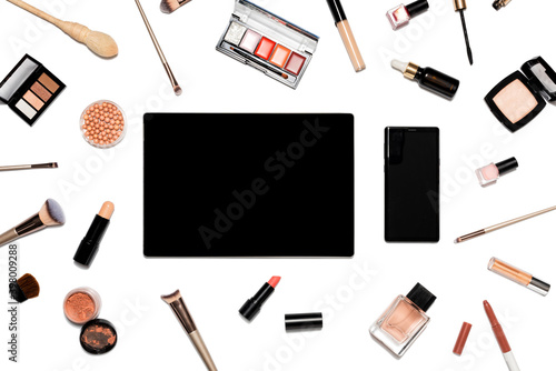 Decorative cosmetics and makeup tools on white background with tablet and phone. Online shopping concept. Frame composition with copy space. Flat lay or top view
