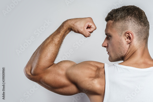 Young bodybuilder man showing his muscular arm photo