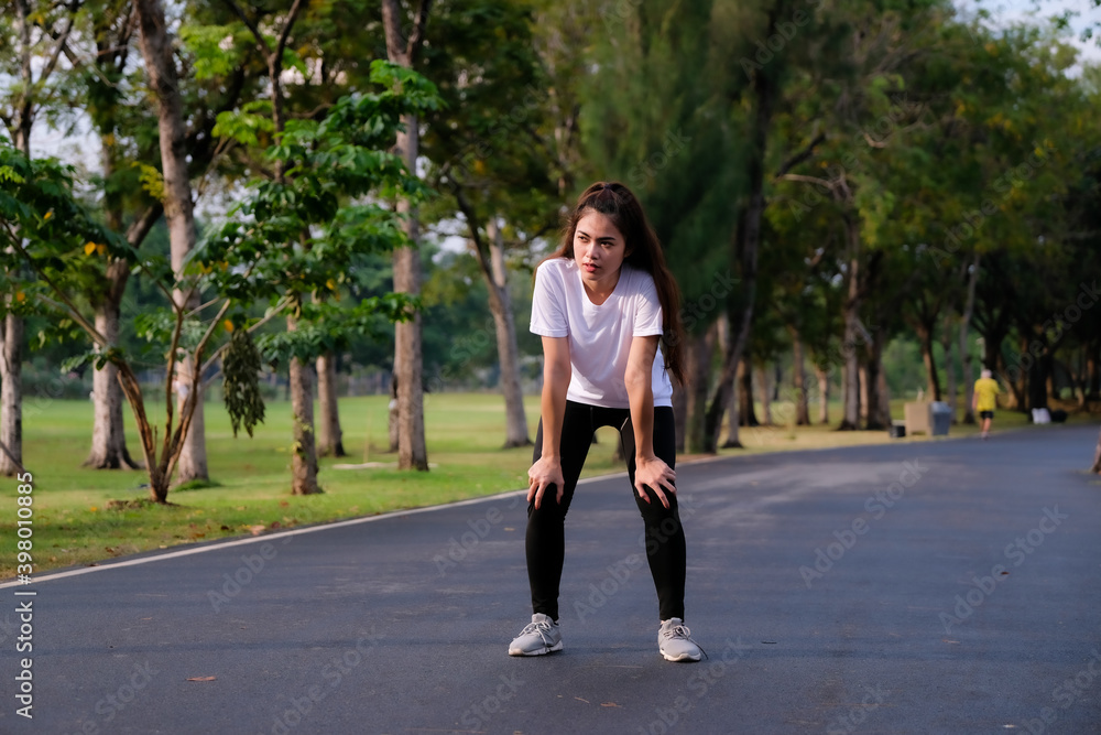 Young beautiful sport woman tired and exhausted breathing. Sportswoman taking break from running workout at a park in morning.