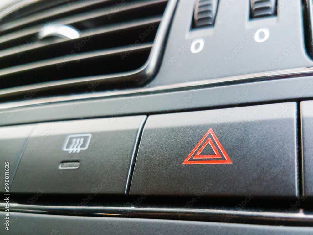Emergency warning button with triangle pictogram on panel in a car