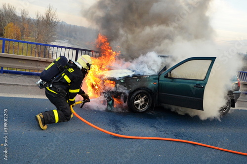Quadro em tela A firefighter with a helmet and a breathing apparatus extinguishes a fully invol