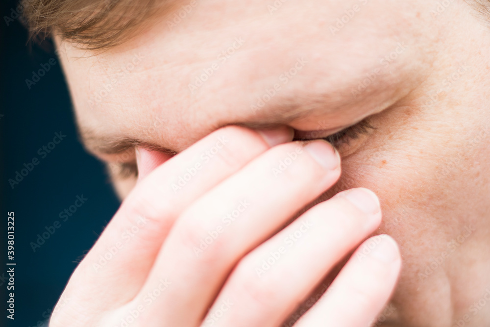Tired young man massaging nose bridge. Businessman experiences discomfort from long work at computer. Bad eye vision concept. Tired young man massaging nose bridge. Businessman experiences discomfort from long work at computer. Bad eye vision concept.