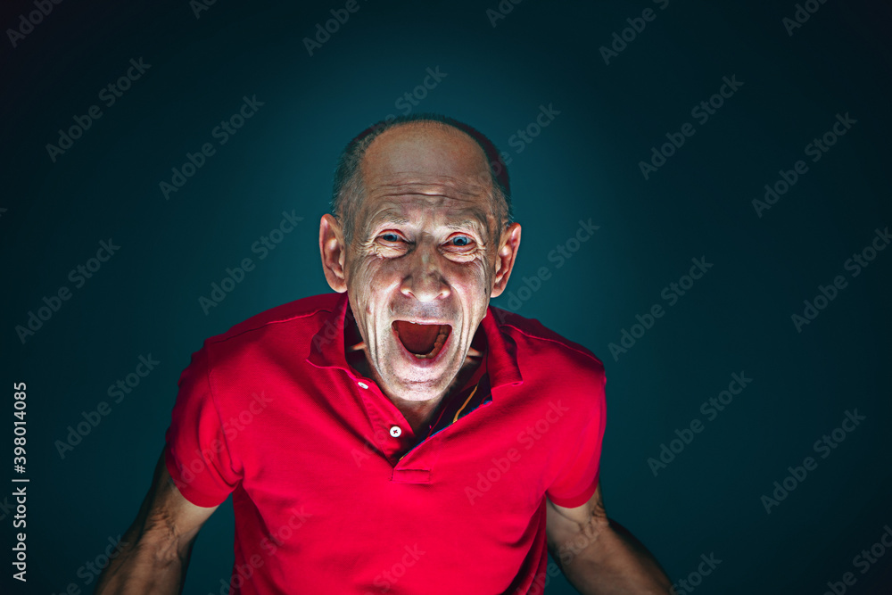 Fototapeta premium Screaming. Portrait of crazy scared and shocked caucasian man isolated on dark background. Copyspace for ad. Bright facial expression, human emotions concept. Watching horror on TV, cinema.