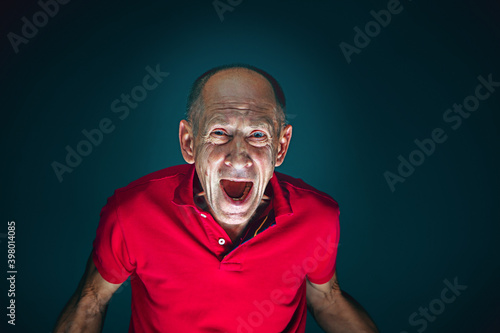 Screaming. Portrait of crazy scared and shocked caucasian man isolated on dark background. Copyspace for ad. Bright facial expression, human emotions concept. Watching horror on TV, cinema.