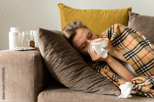 Woman with a runny nose symptom lying under the blanket at home