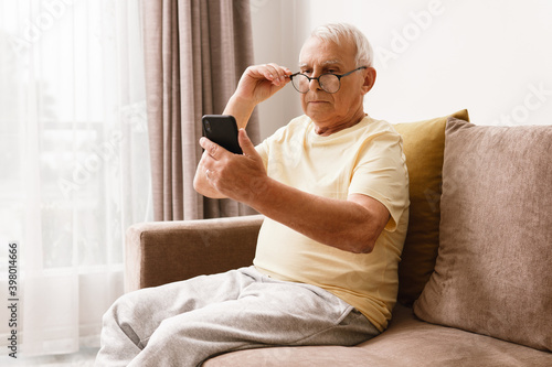 Senior man wearing eyeglasses is using smartphone © blackday