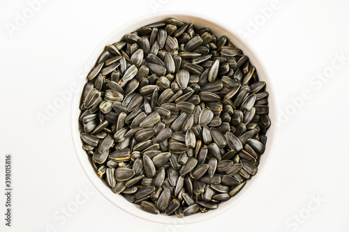 Sunflower seeds in the bowl on the white background, large group of seeds, high angle view