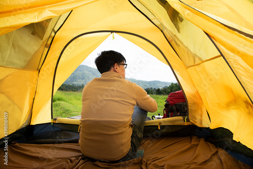 Asian man sitting inside the tent enjoying total freedom with tent camping on the mountain. summer holiday and enjoy