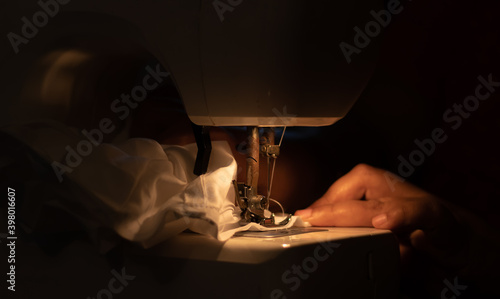 Schilderij op canvas Woman hands using the sewing machine to sew a pant.