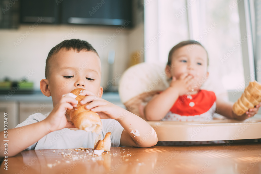 Brother and sister in the kitchen eating tubes with custard or protein cream Brother and sister in the kitchen eating tubes with custard or protein cream