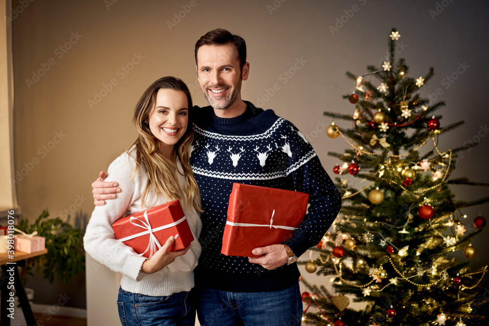 Smiling couple holding Christmas presents at home Smiling couple holding Christmas presents at home
