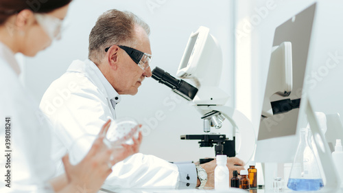 scientists using a microscope to study bacteria in a Petri dish.