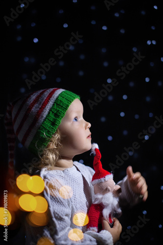 Charming girl Christmas Santa hat black background with star lanterns. portrait todller against starry sky. photo