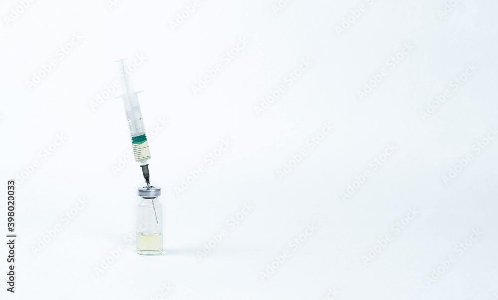 On a white background, a syringe inserted into a vial of vaccine. On a white background, a syringe inserted into a vial of vaccine.