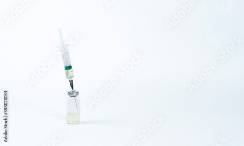 On a white background, a syringe inserted into a vial of vaccine.