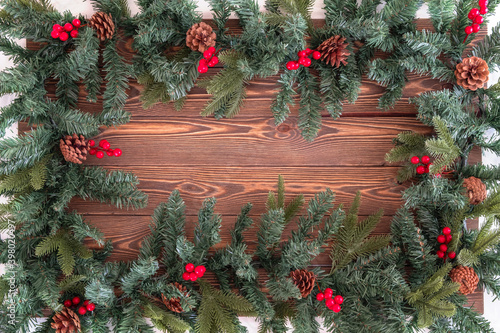 Christmas branch on a wooden table with pine cones and red berries