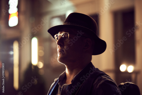 Portrait of a street musician man in a hat with a violin in the night city.