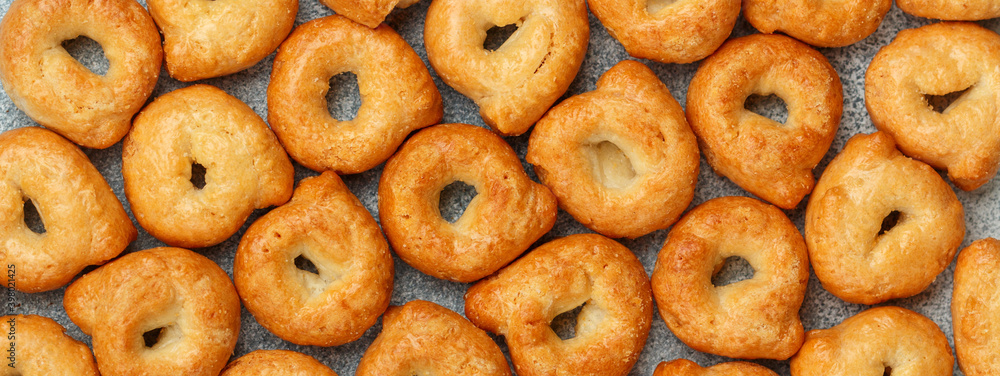 Tarallini-traditional Italian small bagels. Taralli. Delicious snack close-up. Culinary background. Selective focus, top view, long image, banner
