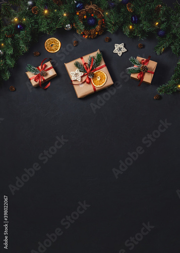 Christmas background with copy space. Gift boxes and fir branches on black texture background. Instagram stories