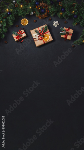 Christmas background with copy space. Gift boxes and fir branches on black texture background. Instagram stories photo