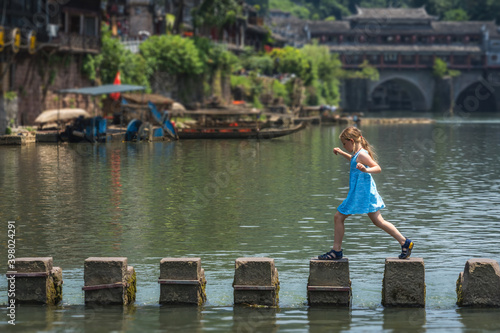 Young Caucasian girl on stepping stones in Fenghuang photo