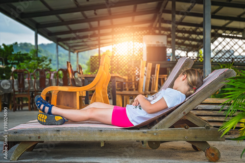 Cute Caucasian girl resting on a reclining wooden chair