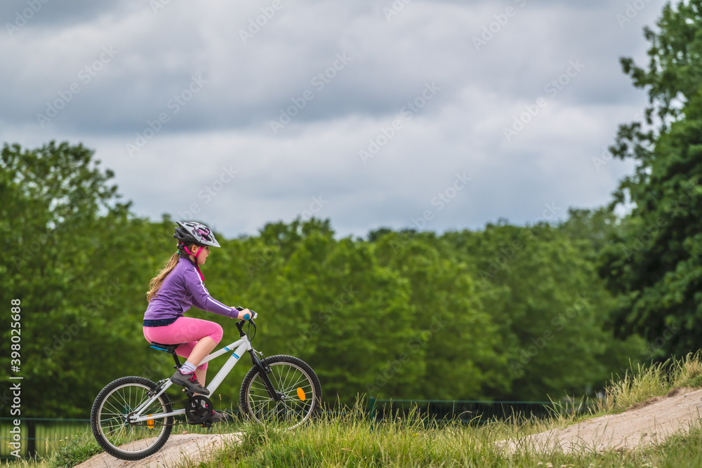 Young girl riding on her bicycle on a dirt race track Young girl riding on her bicycle on a dirt race track