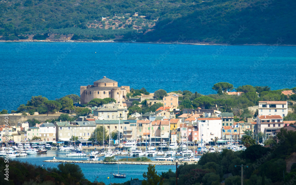 Panorama of beautiful Saint Florent fishing village, harbour and the citadel in the background. Corsica, France