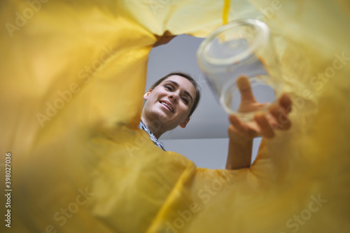 Obraz na plátně waste sorting - woman throwing glass jar in bag for recycling at home