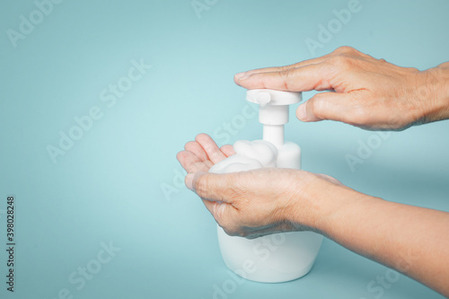 soap foam in old people's hand with the other press dispenser pump of white bottle for cleaning hand , new normal lifestyle concept